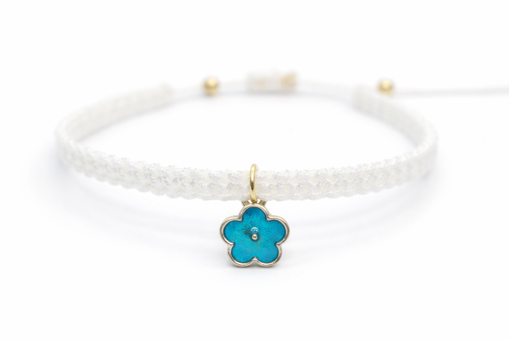 White braided bracelet with a turquoise flower charm on a white background