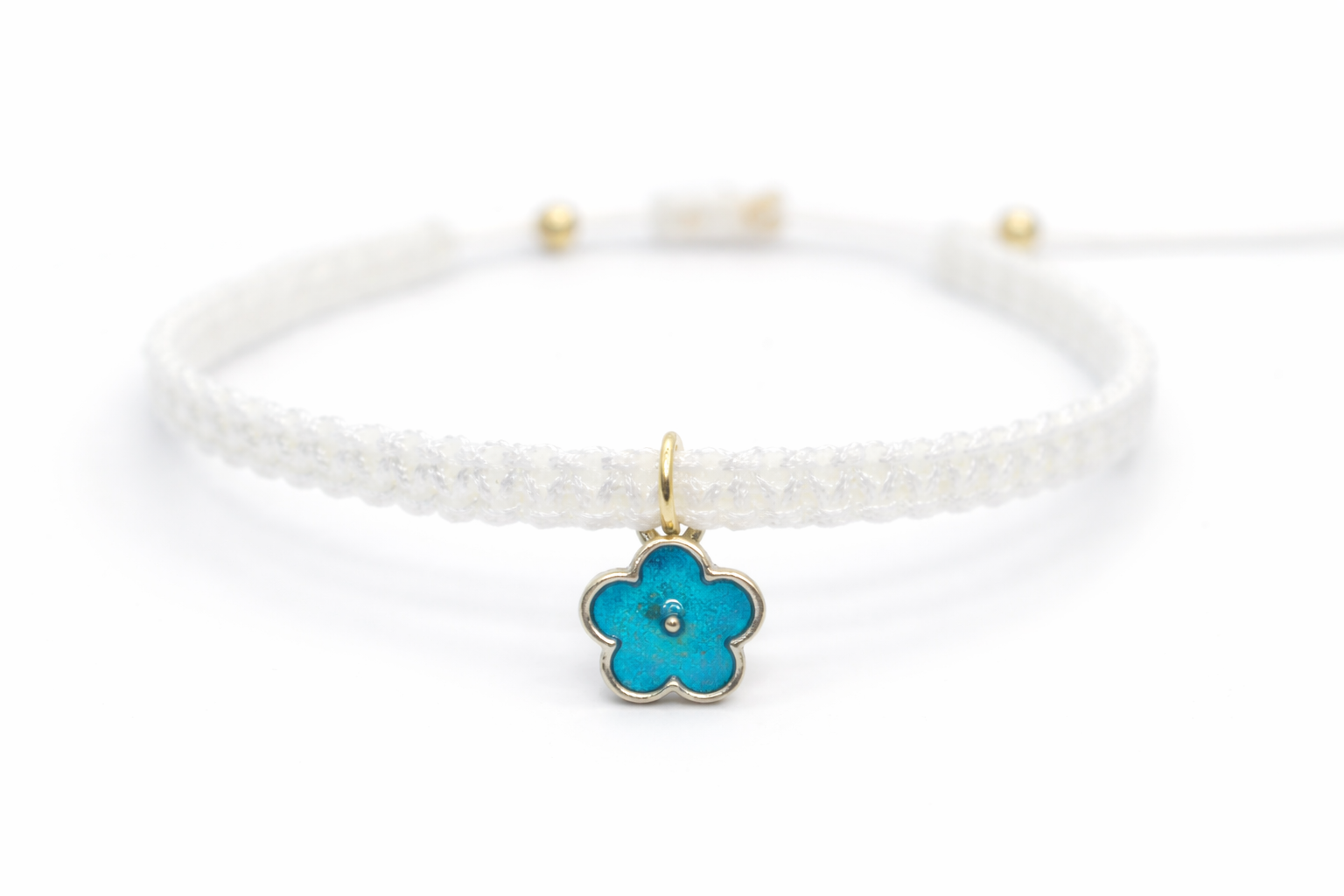 White braided bracelet with a turquoise flower charm on a white background