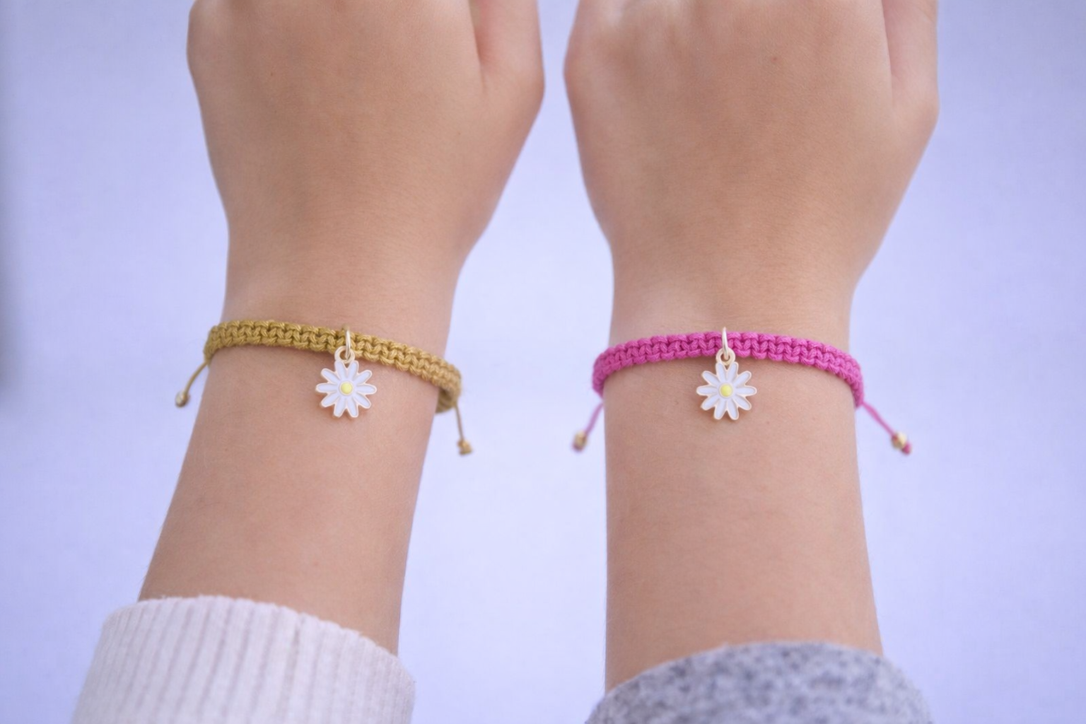Woman wearing dainty daisy flower charm bracelet, layered minimalist jewelry look