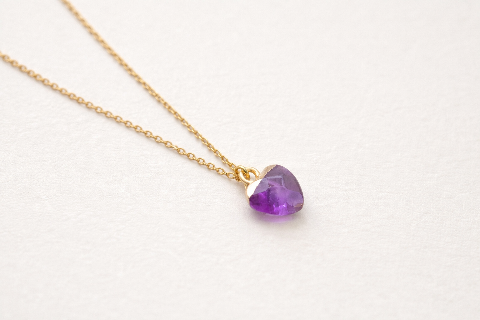 Necklace with a purple teardrop-shaped pendant on a white background