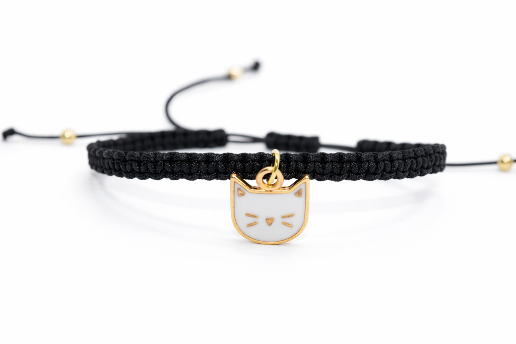 Black braided bracelet with a cat-shaped gold charm on a white background