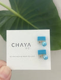 Pair of blue earrings on a Chaya card with a green leaf background