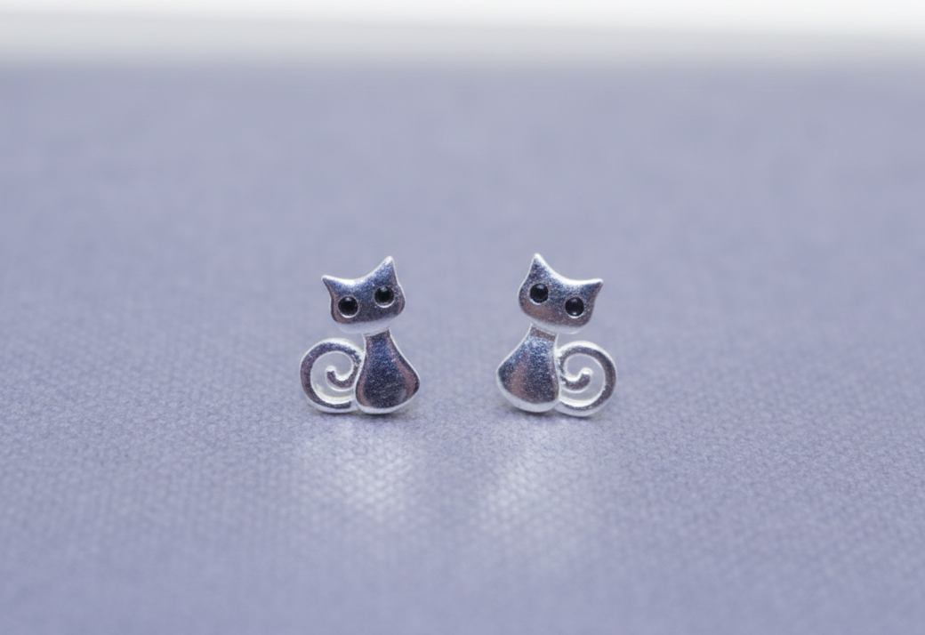 Silver cat-shaped earrings on a light gray background