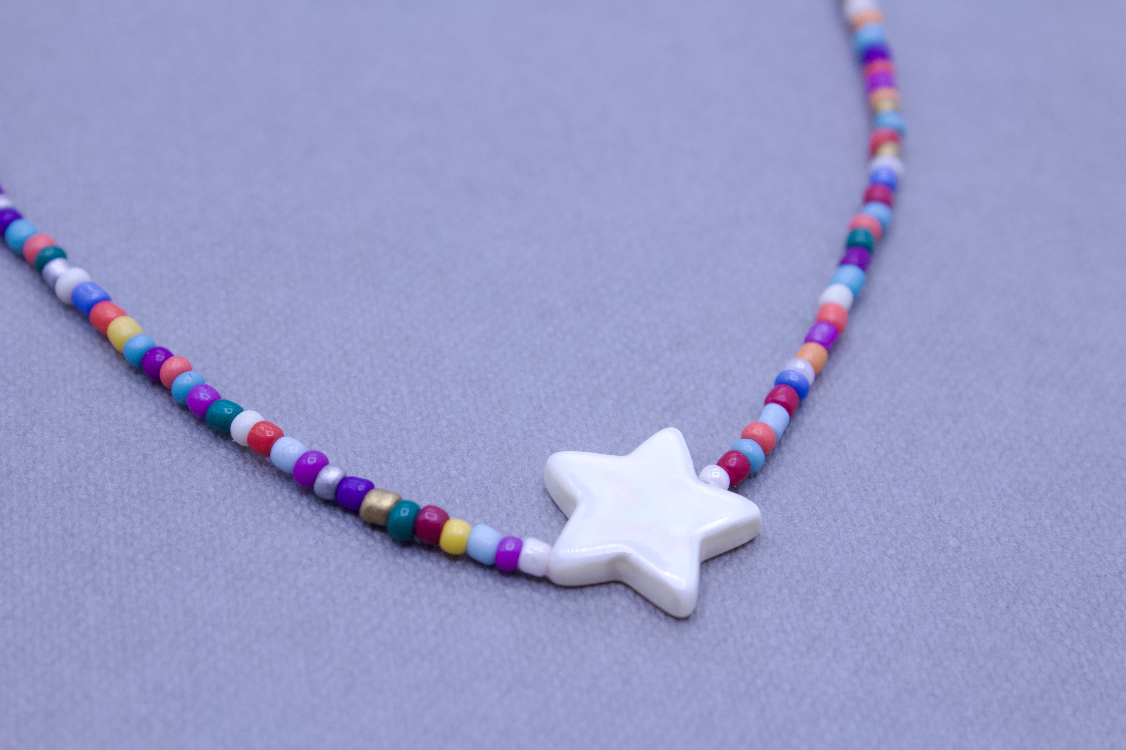 close up of colorful seed bead necklace shell star charm