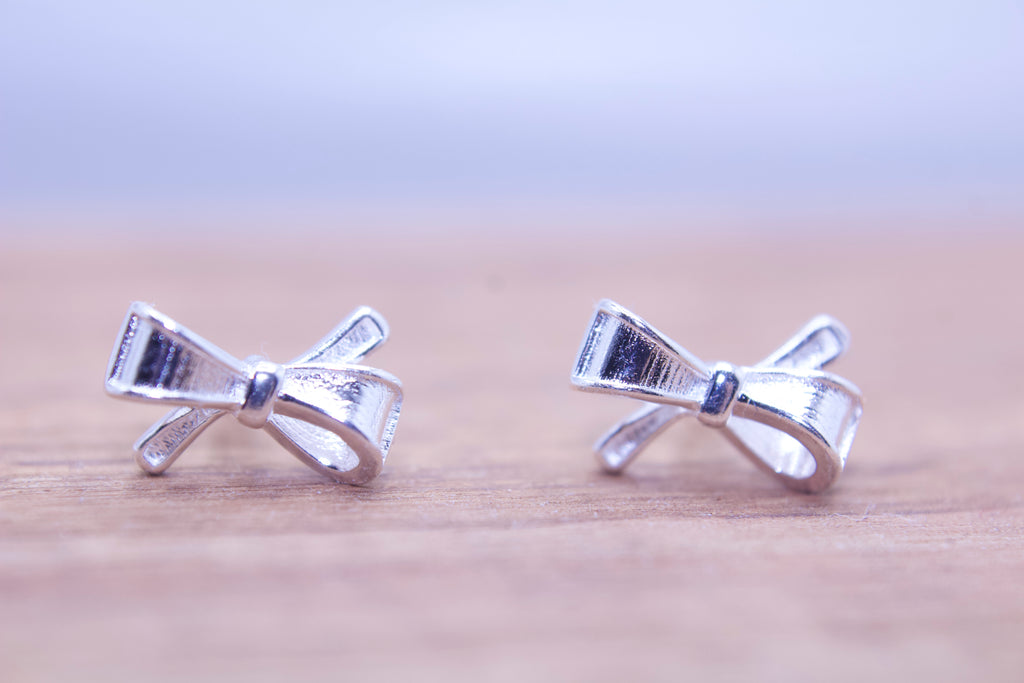 close up of silver bow stud earrings delicate minimalist design