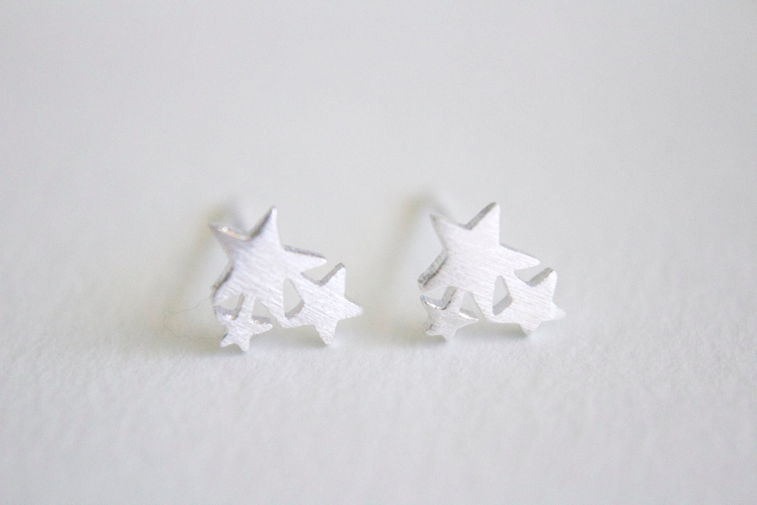 close up silver star stud earrings on white background