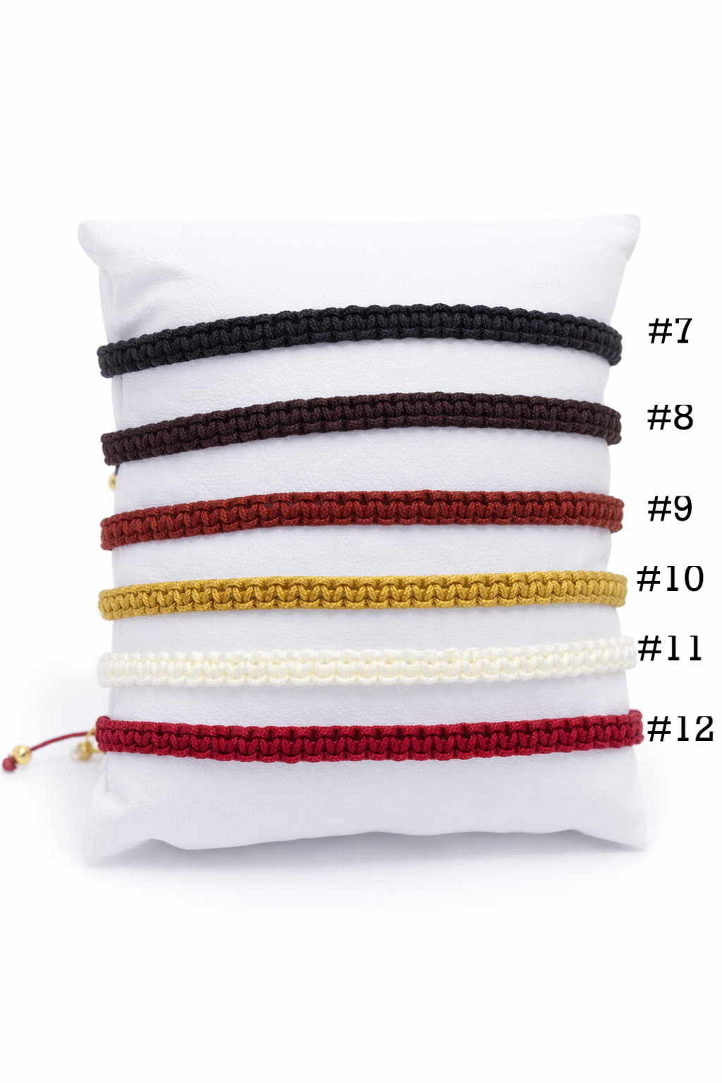 Set of bracelets on a white pillow with numbered labels on a white background