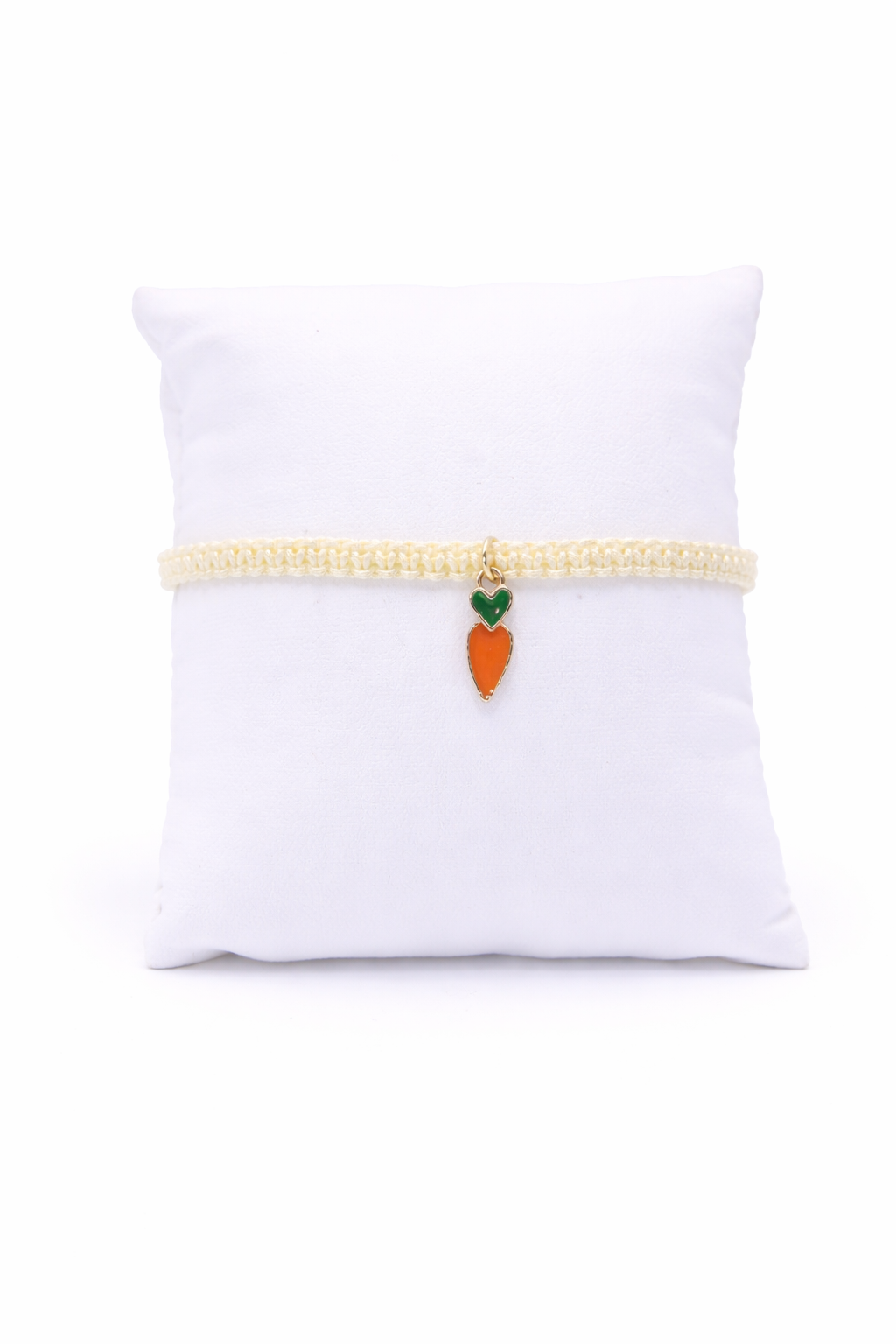 Bracelet with a carrot charm on a white pillow