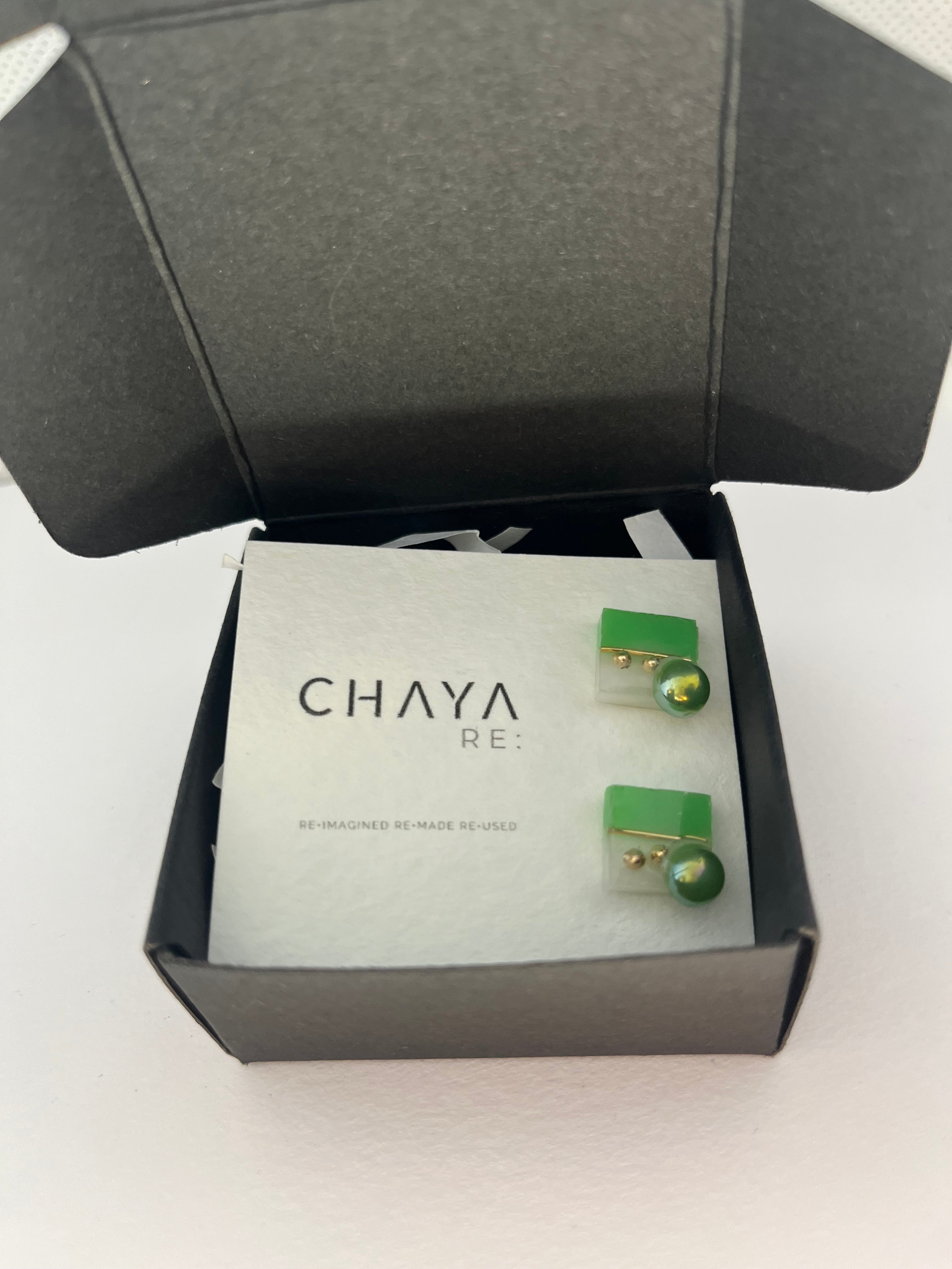 Green earrings in a Chaya box on a white background