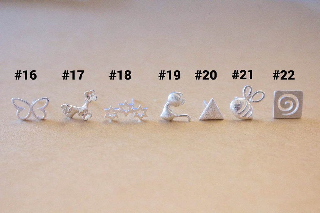 Set of silver earrings on a beige surface with numbered labels.