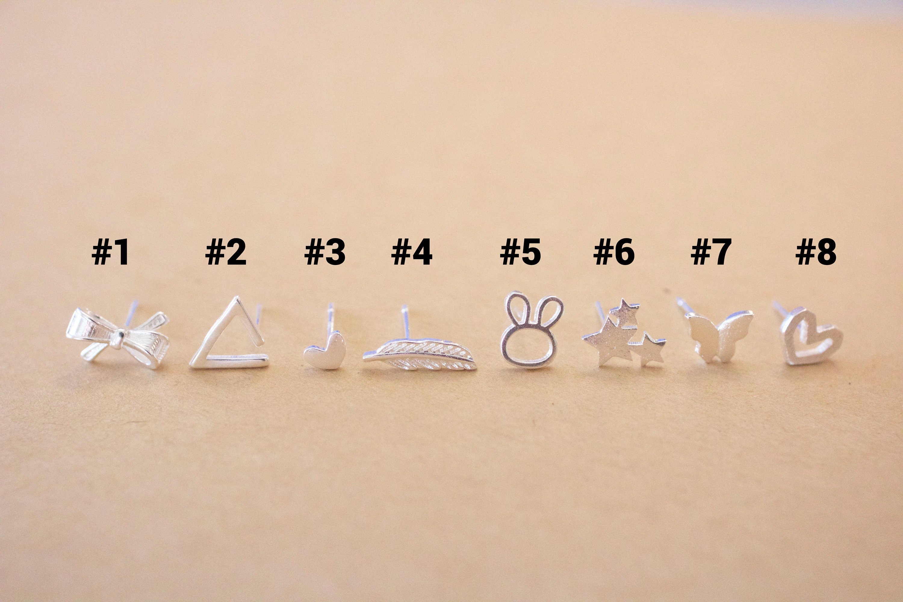 Set of eight pairs of silver earrings on a beige background