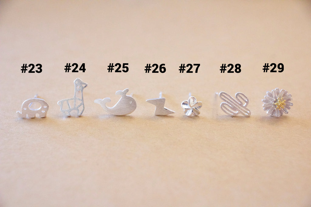 Set of silver earrings with various designs on a beige background