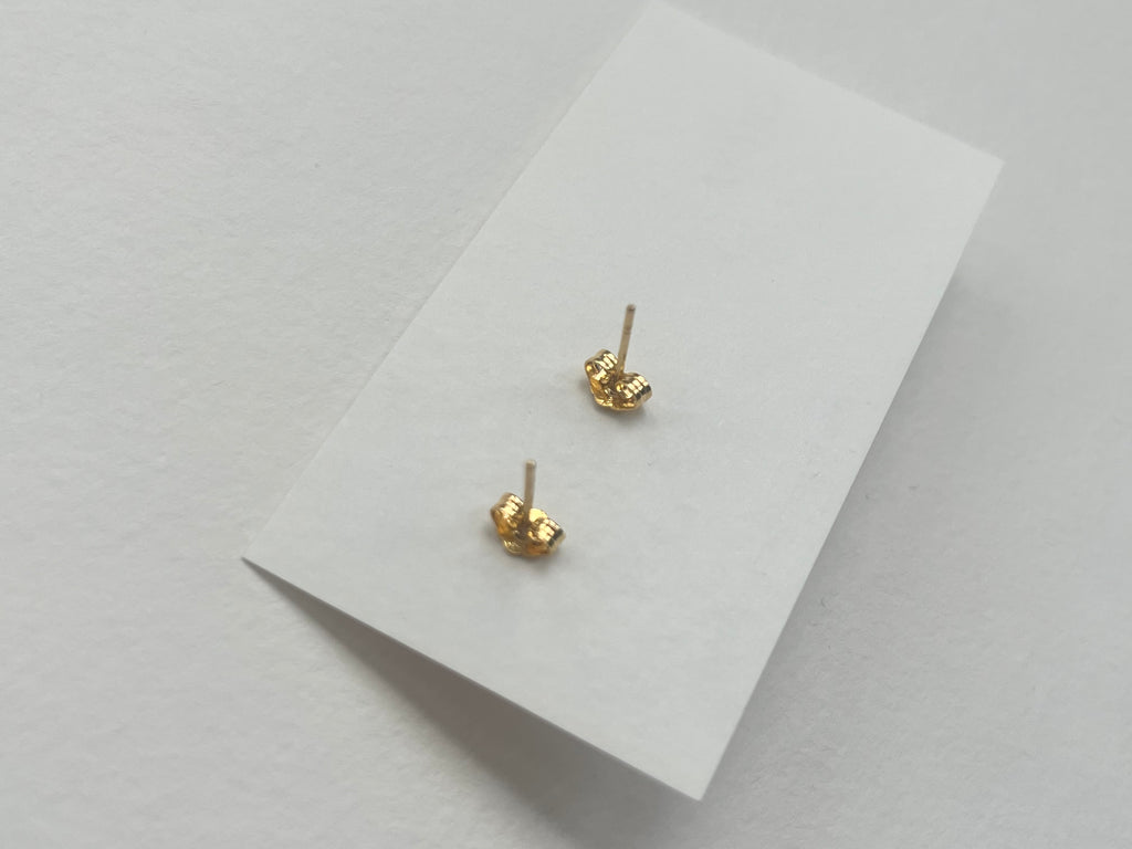 Gold earrings on a white card with a light gray background