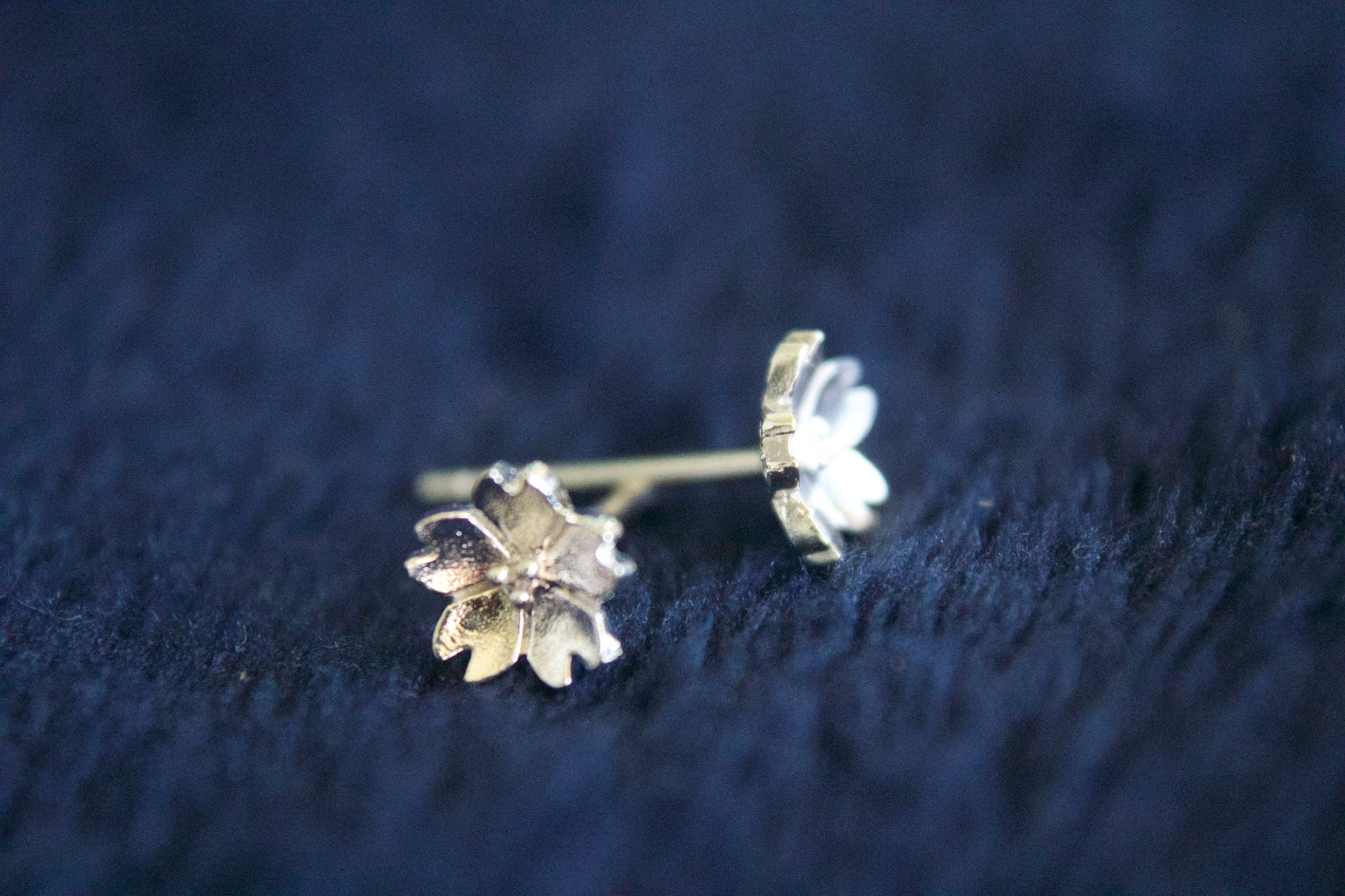 Flower-shaped earrings on a dark blue textured surface