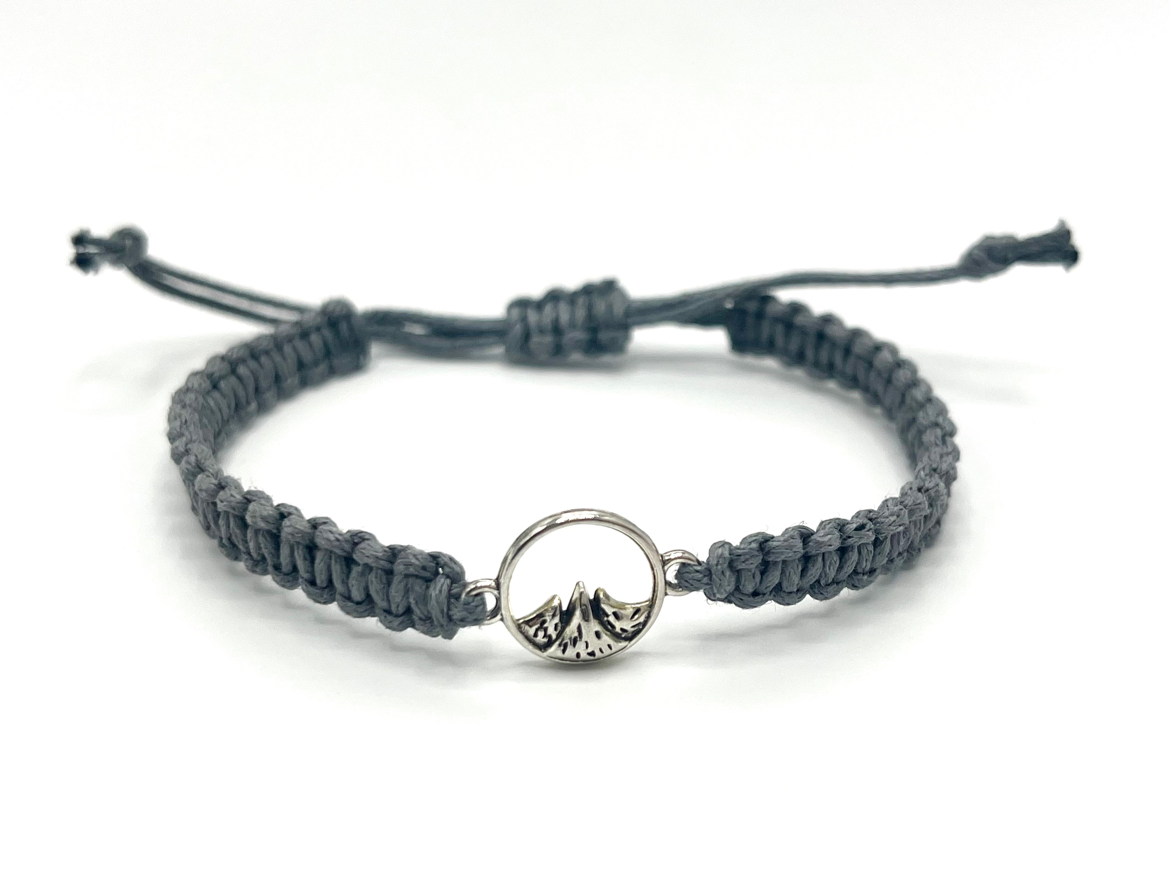 Gray braided bracelet with a silver ring and mountain design on a white background