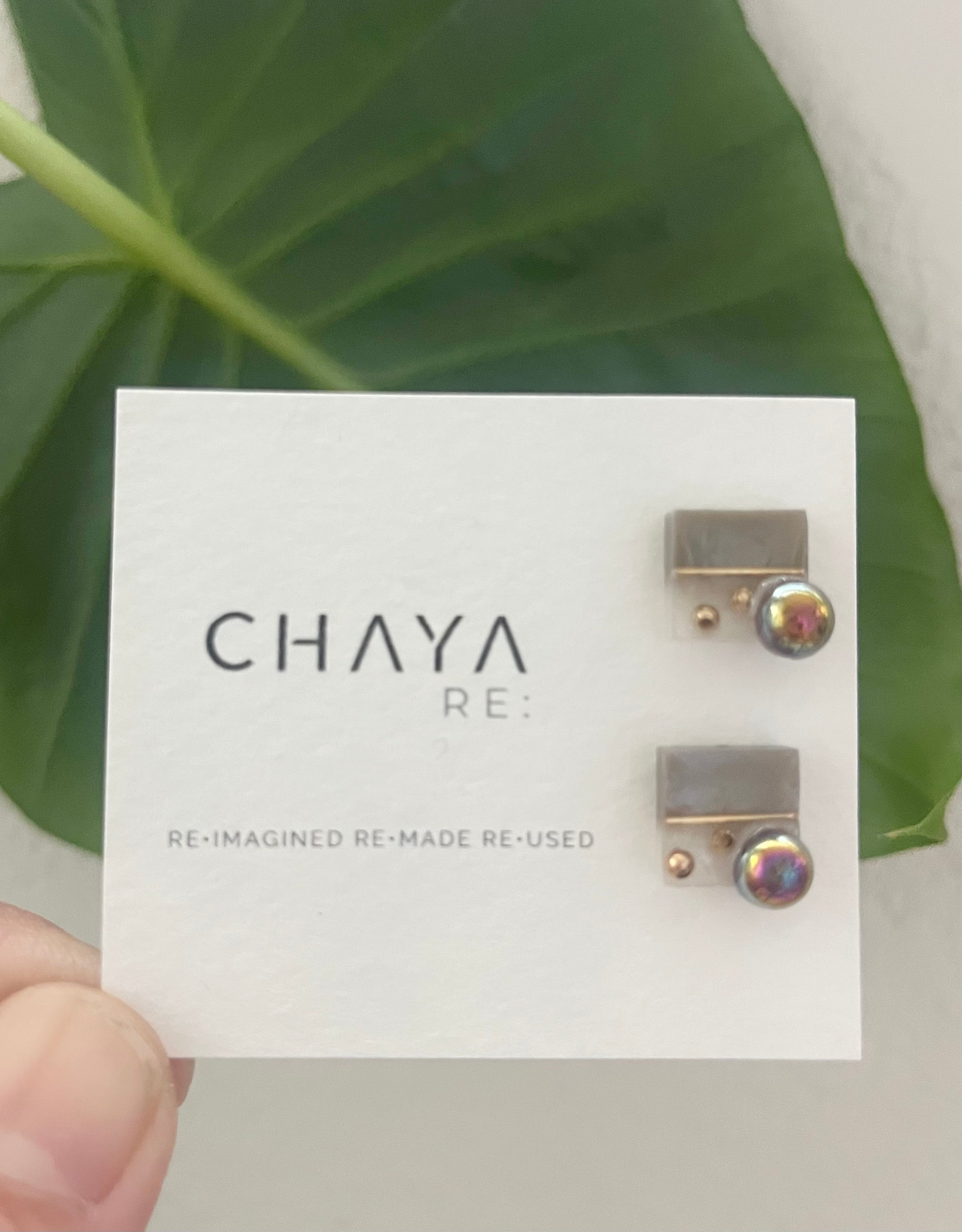 Earrings on a 'Chaya' branded card with green leaves in the background
