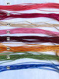 Set of eight strands of thread in various colors on a white background