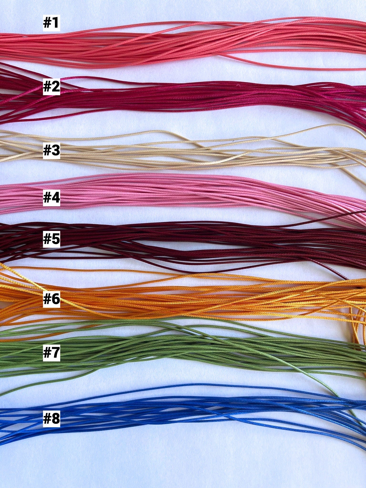 Set of eight strands of thread in various colors on a white background