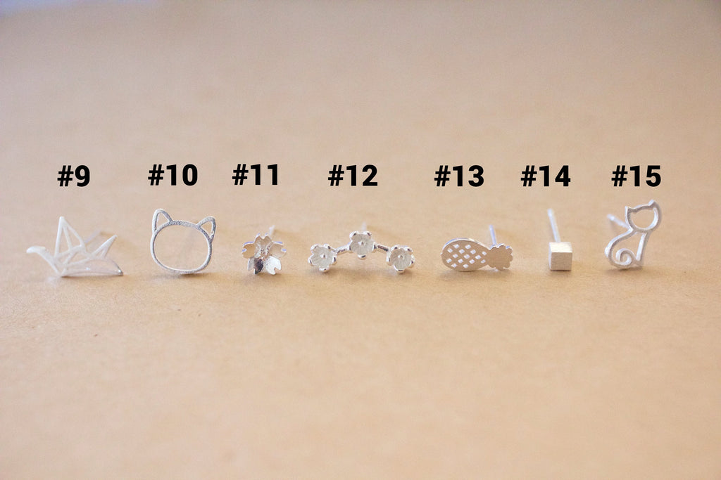 Set of silver earrings with various designs on a beige background
