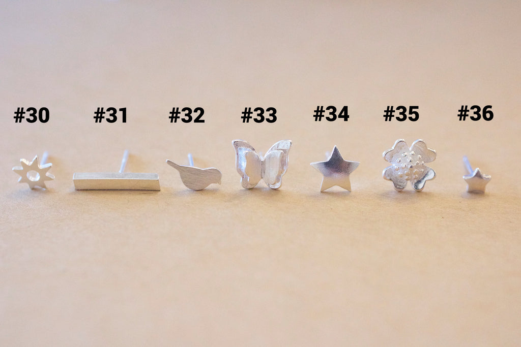 Set of silver earrings with various designs on a beige background