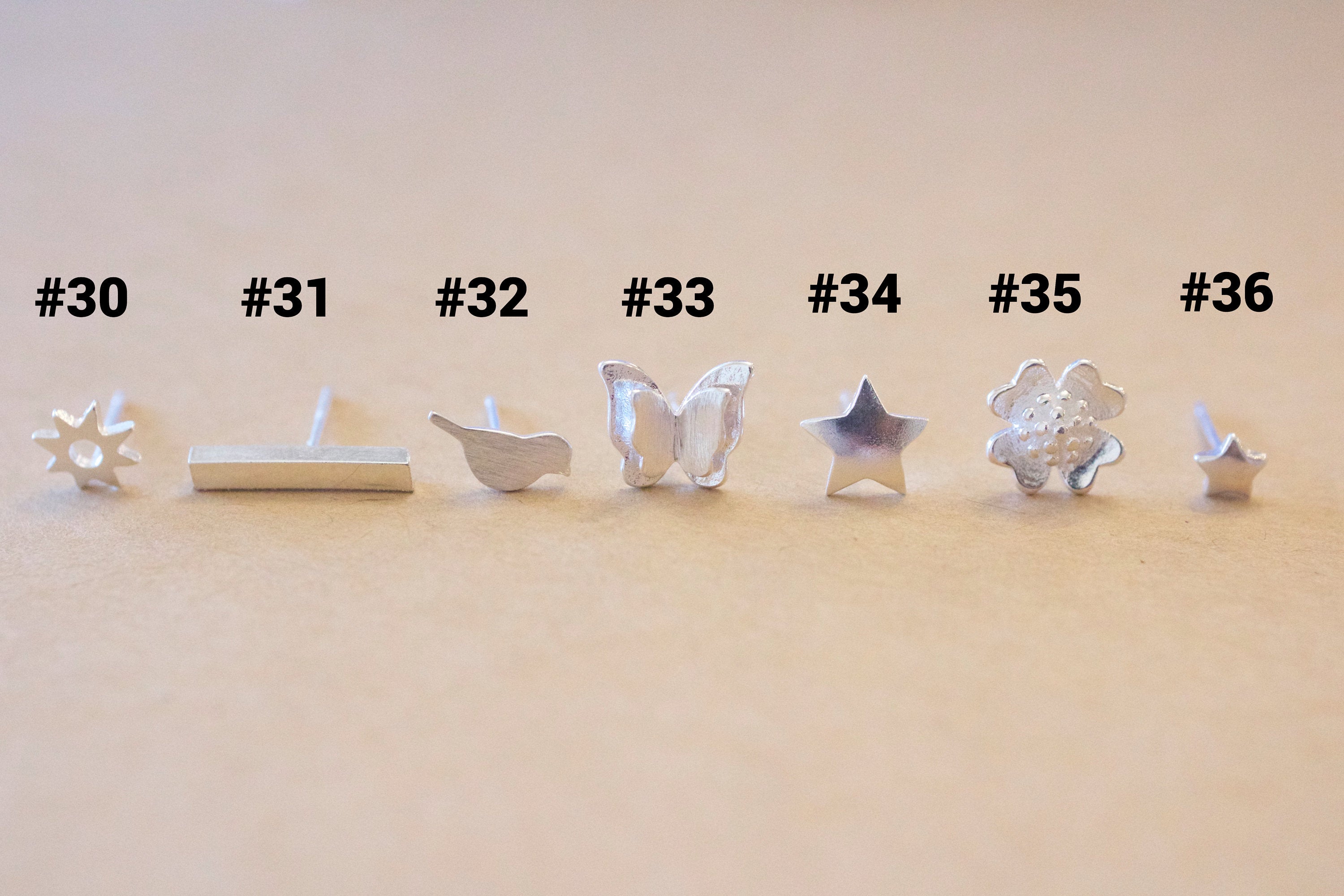 Set of silver earrings with various designs on a beige background