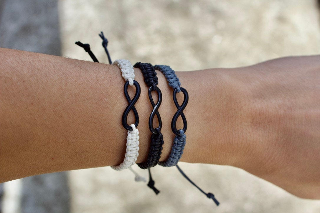 Wrist wearing multiple infinity bracelet on a blurred natural background