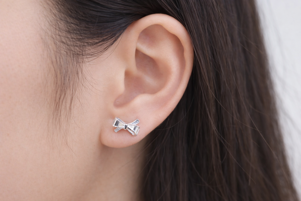 silver bow stud earrings worn minimalist jewelry look