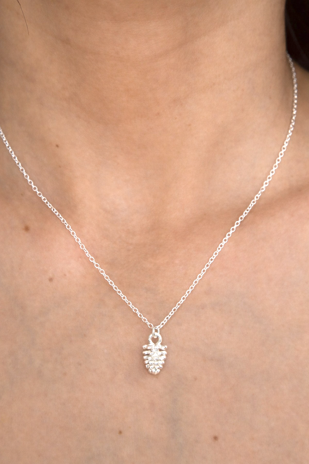 Silver necklace with a small pendant on a person's neck