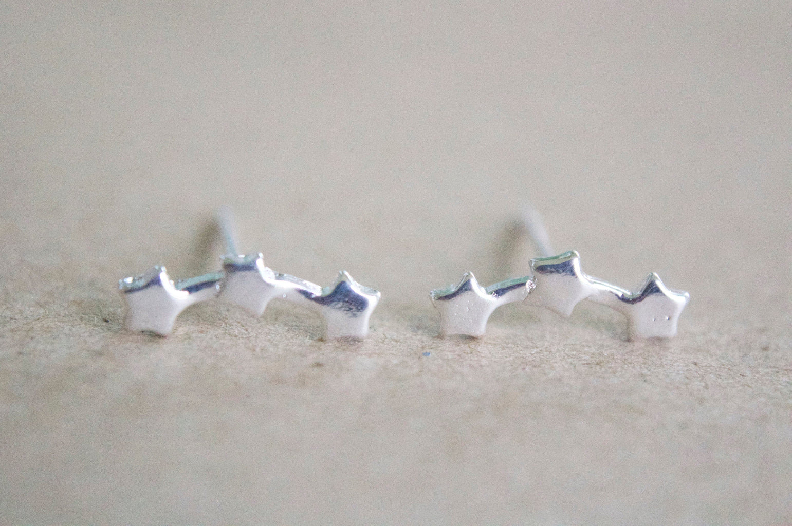 tiny sterling silver star studs close up on white background