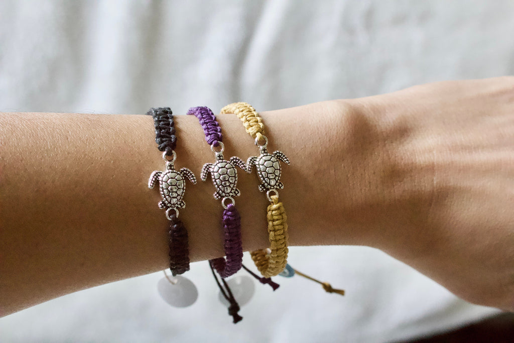 Three turtle-themed bracelets on a wrist against a neutral background
