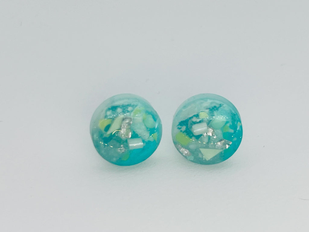 Pair of turquoise earrings with a speckled design on a light gray background