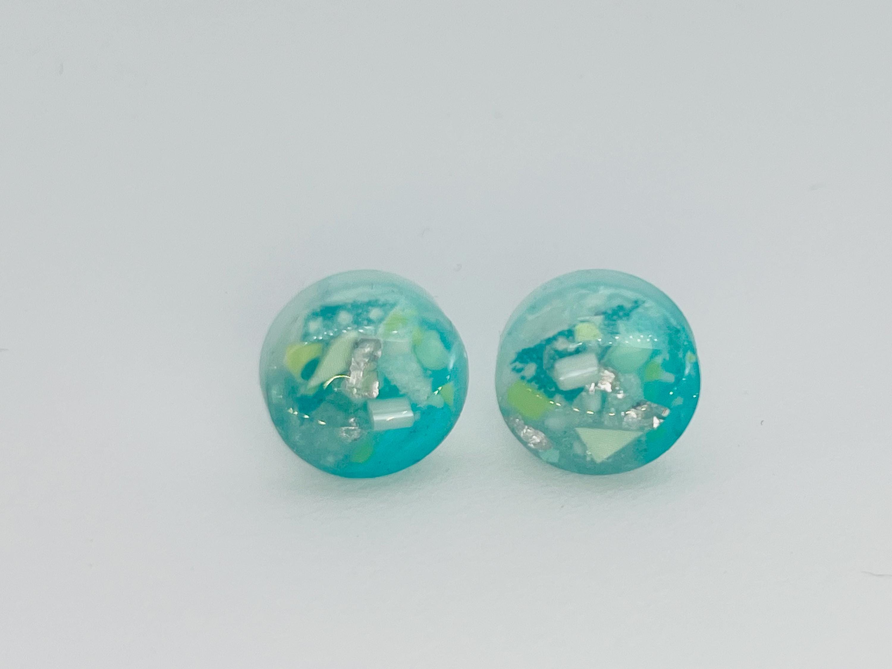 Pair of turquoise earrings with a speckled design on a light gray background