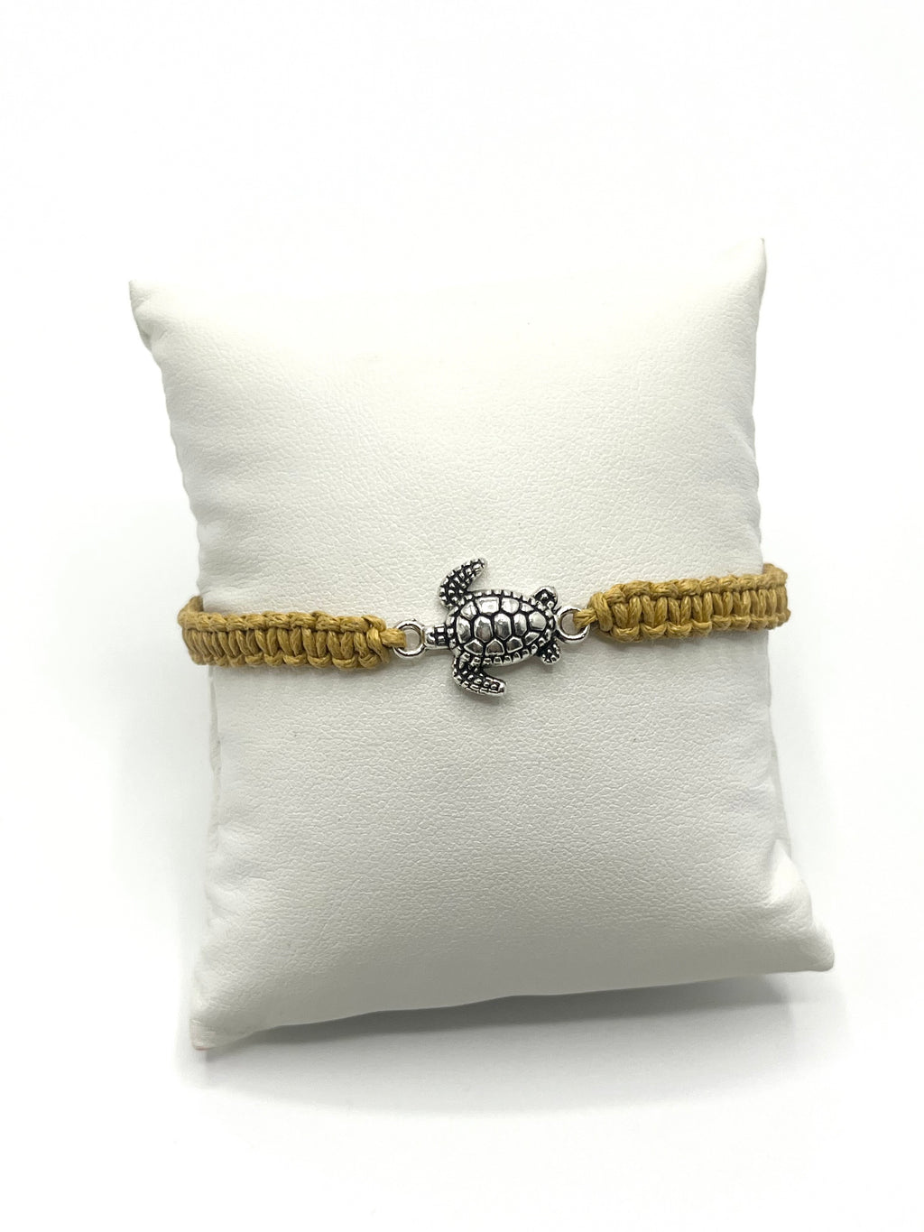 Bracelet with turtle charm on a white pillow