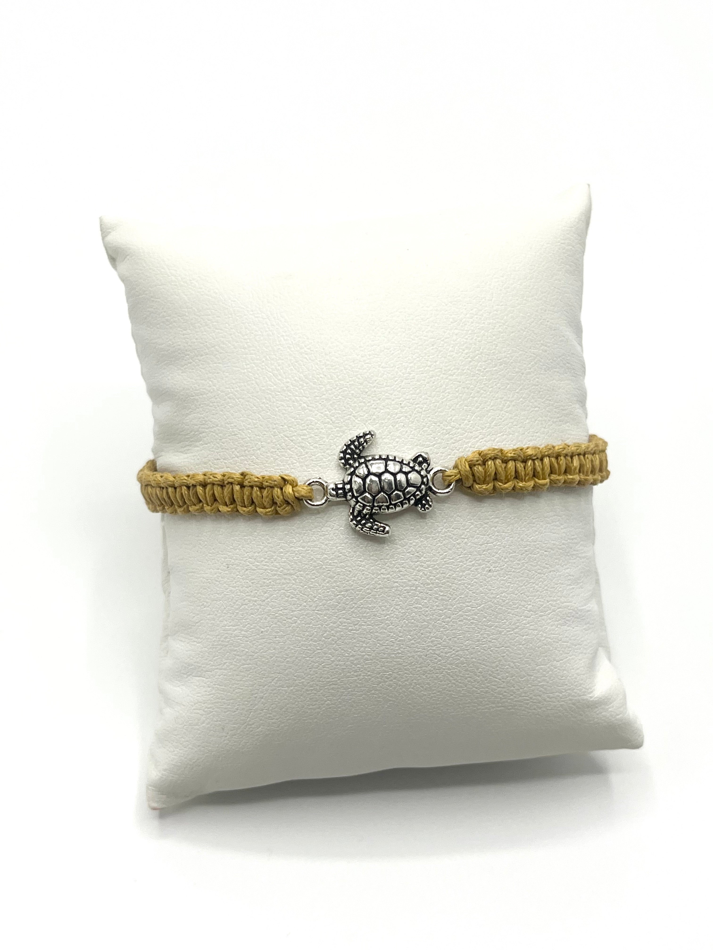 Bracelet with turtle charm on a white pillow