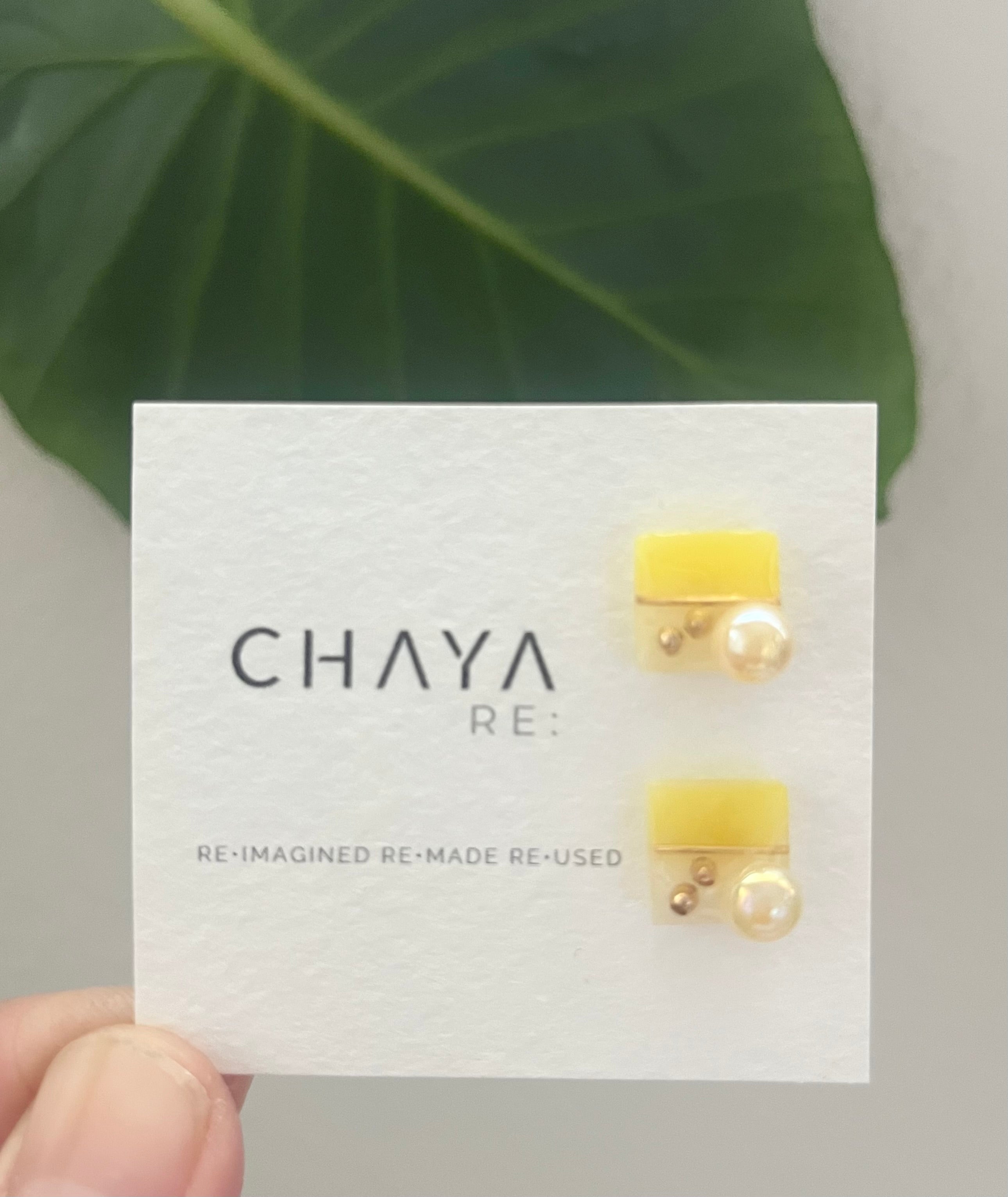 Yellow earrings on a Chaya RE card with a green leaf background